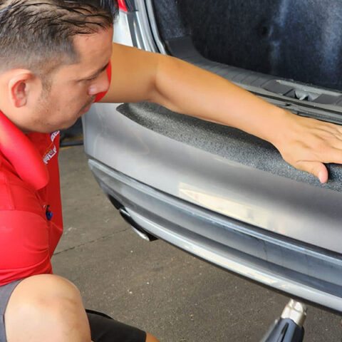 guy in red shirt putting back bumper wrap in trunk area