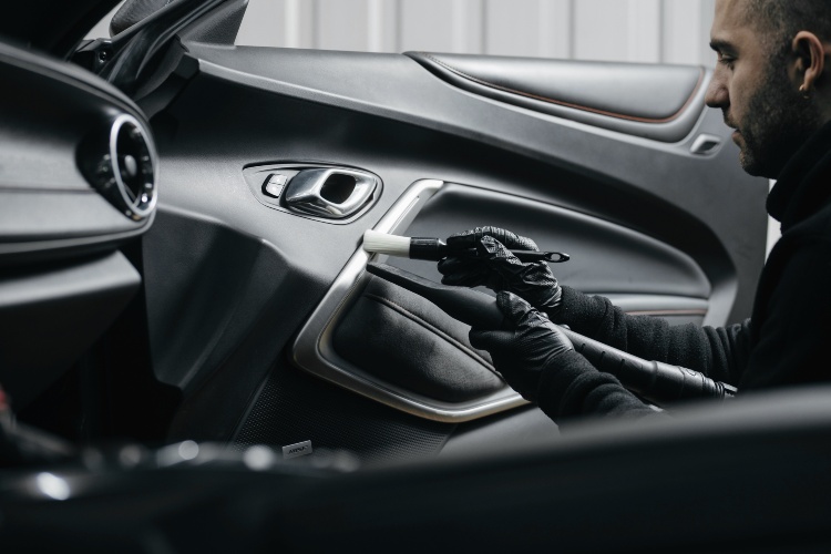 A technician detailing a luxury car door panel and interior trim at Auto Salon of Orlando